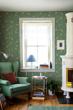 Elmire wallpaper by Sandberg in green in a cosy reading corner with a green wingback chair and tiled stove