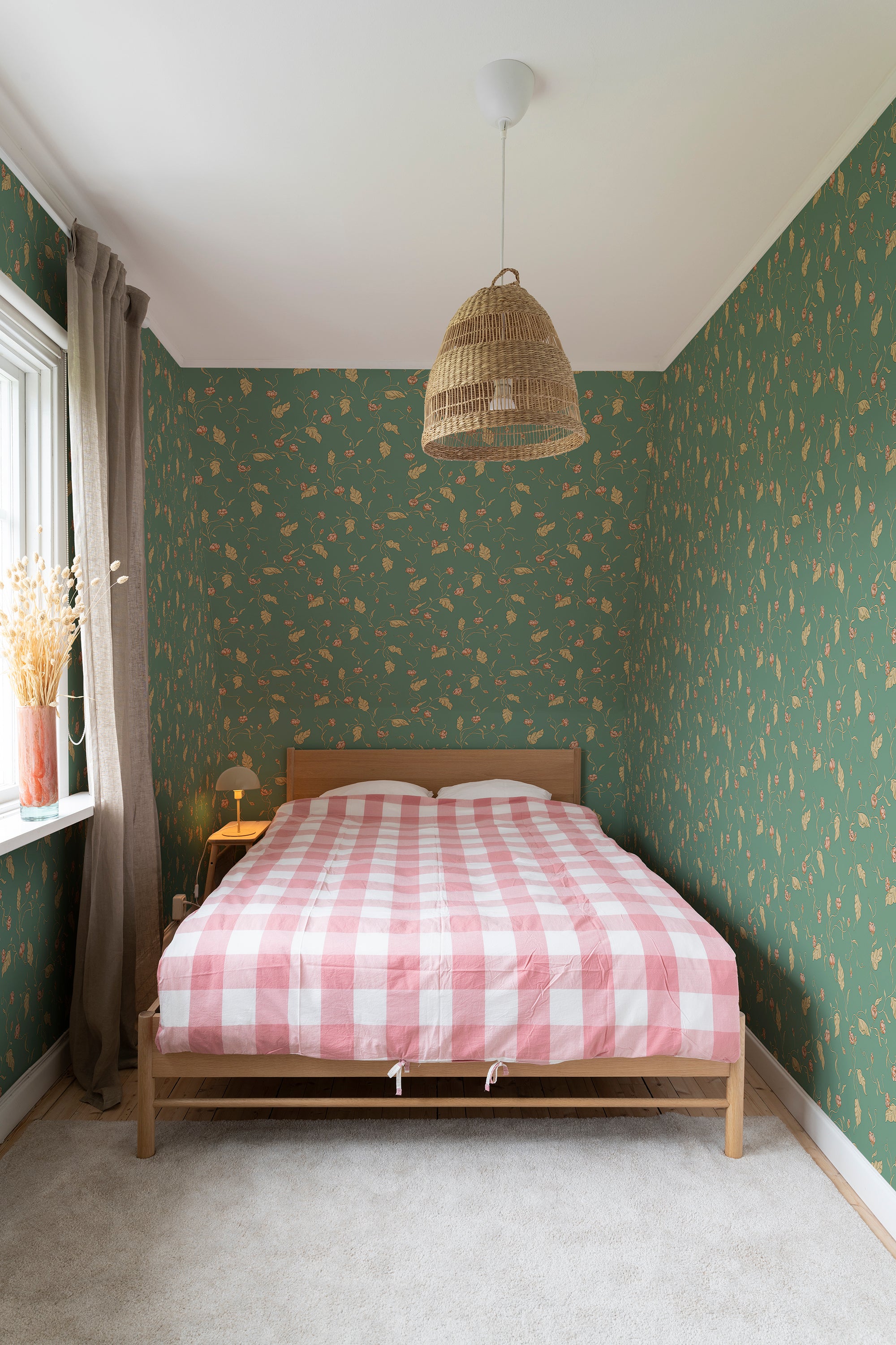 Elmire wallpaper by Sandberg in green in a bedroom with a pink gingham bed and woven pendant lamp