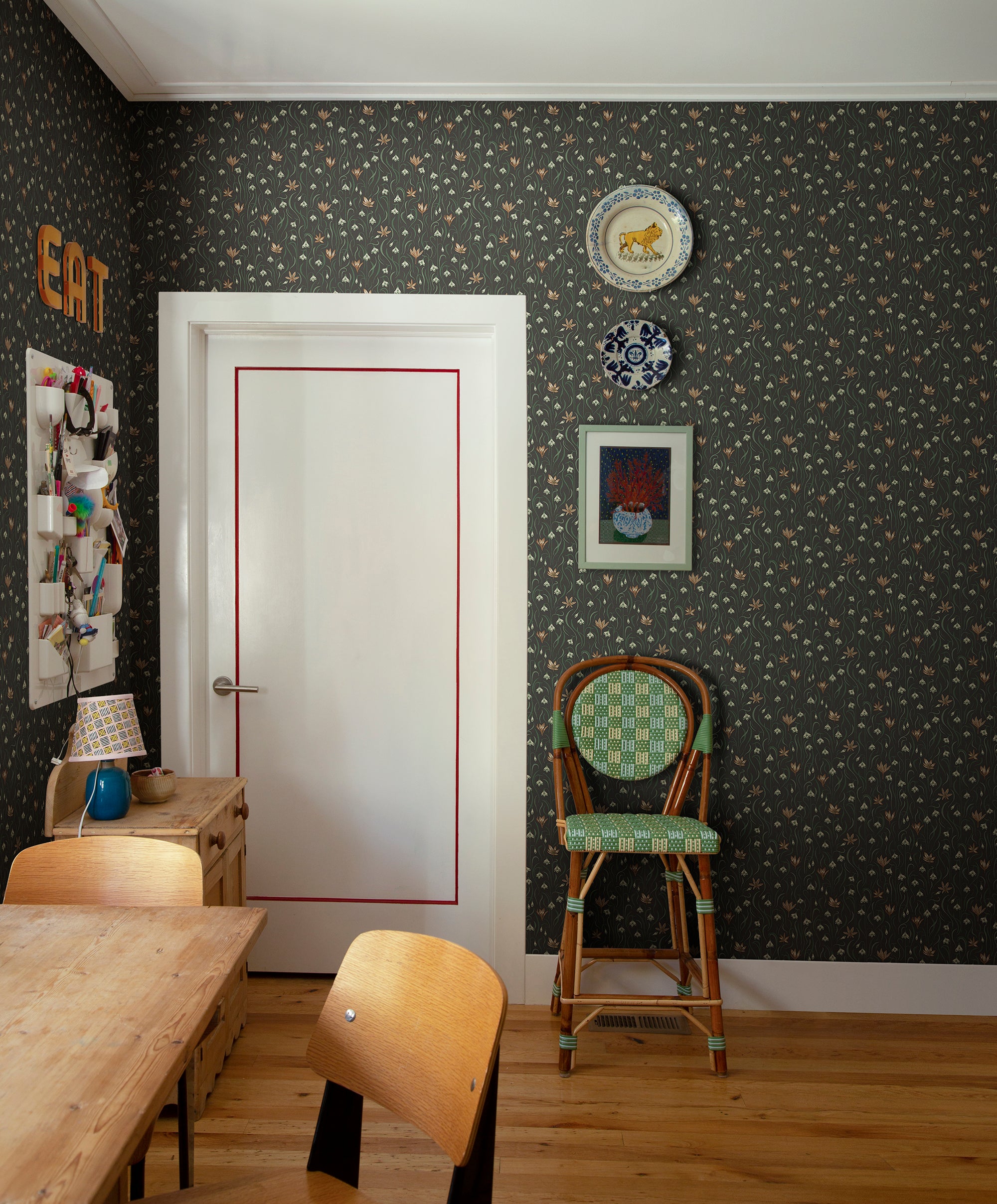 Signe wallpaper by Sandberg in dark charcoal styled in a dining nook with timber chairs, a white door and decorative wall plates