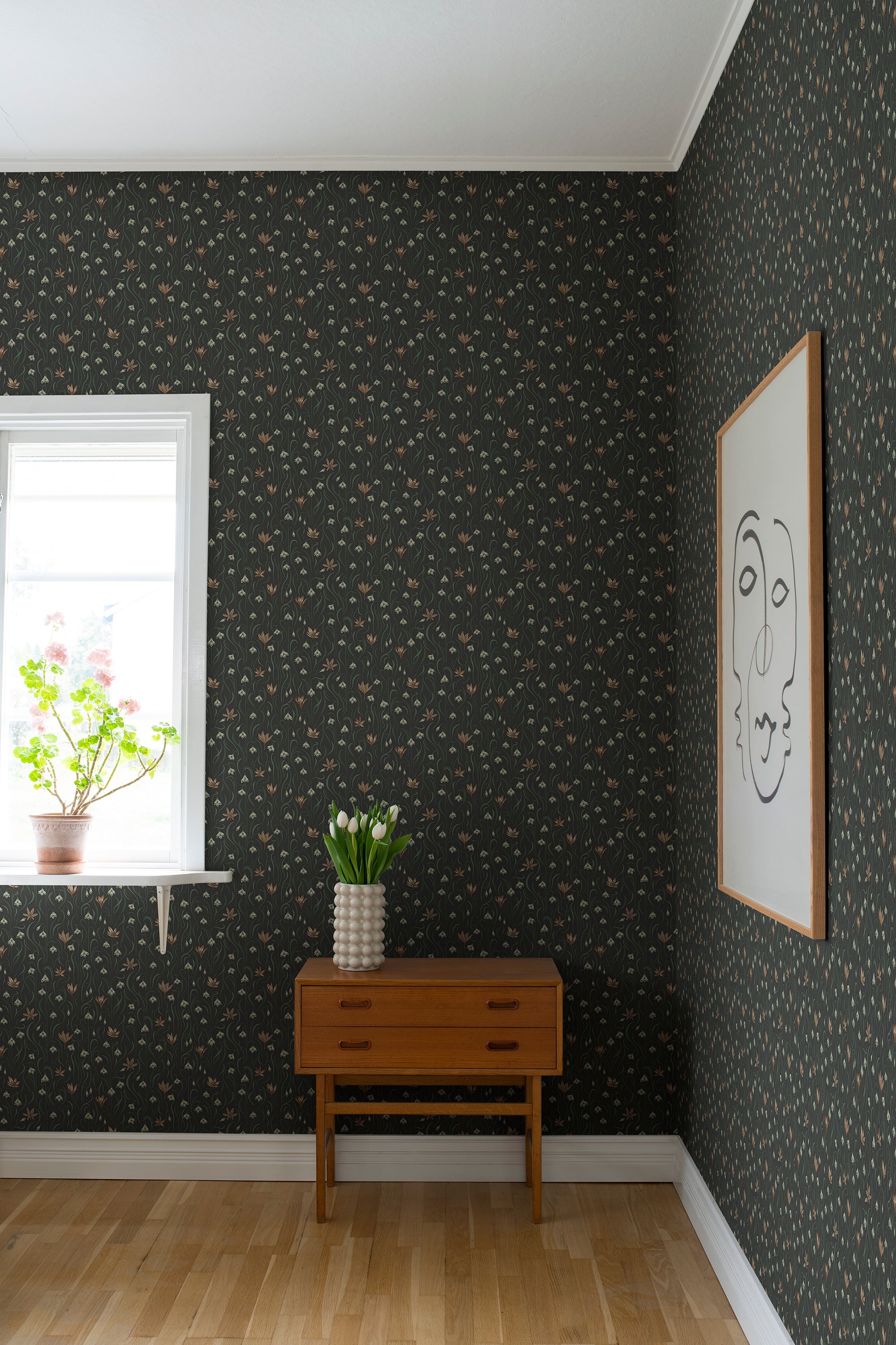 Signe wallpaper by Sandberg in dark green styled in a corner with a teak console, white tulips and a framed line-drawing portrait