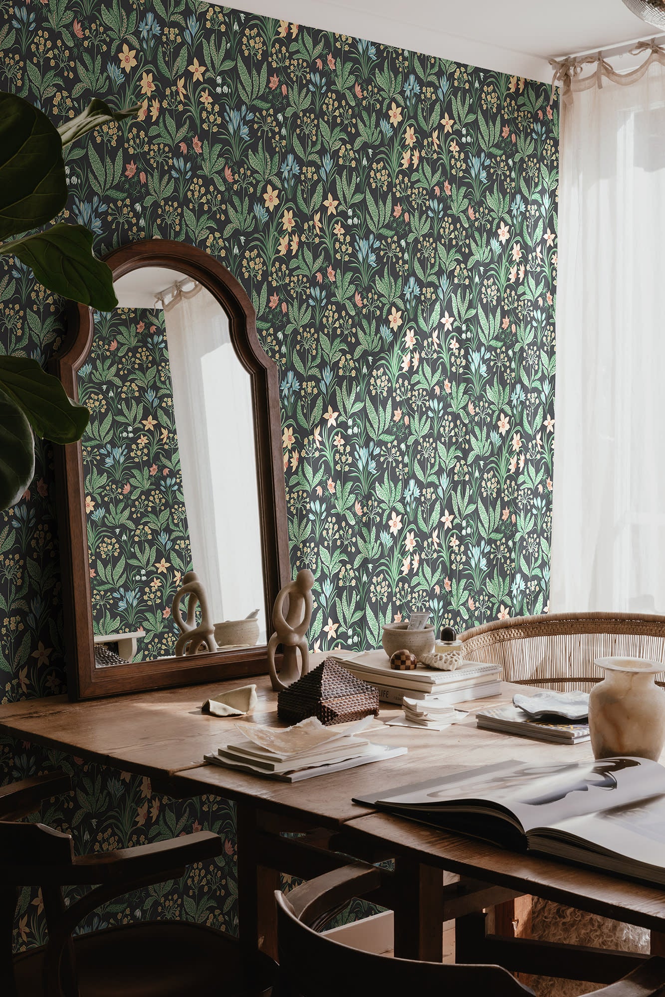 Huset i Solen wallpaper by Sandberg in dark meadow print styled behind a wooden desk with an arched mirror and sheer curtain