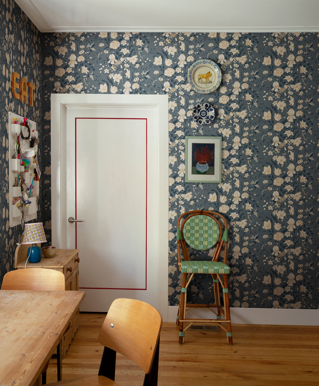 Karins Bukett wallpaper by Sandberg in slate blue in a dining nook with a rattan chair and timber table