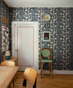 Karins Bukett wallpaper by Sandberg in slate blue in a dining nook with a rattan chair and timber table