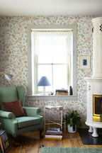 Till Karin wallpaper by Sandberg in cream floral in a sunny corner with green armchair and white tiled stove
