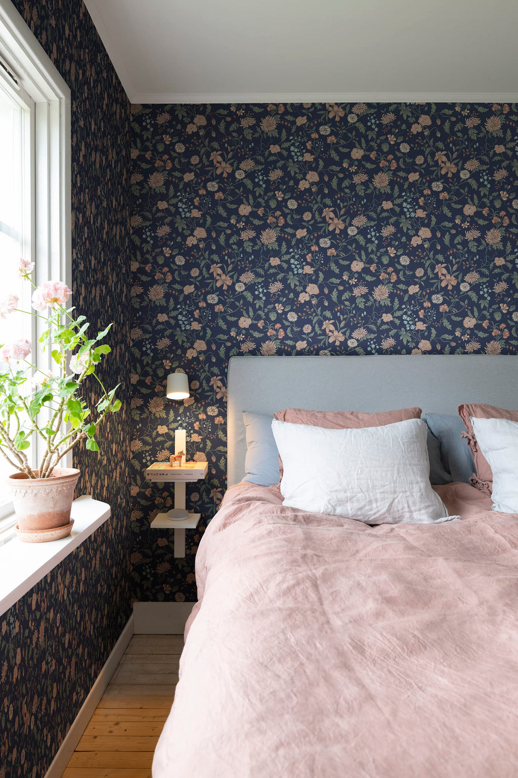 Till Karin wallpaper by Sandberg in navy floral behind a bed with grey headboard and dusty pink linen bedding