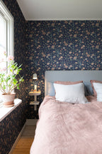 Till Karin wallpaper by Sandberg in navy floral behind a bed with grey headboard and dusty pink linen bedding