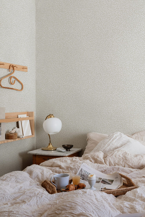 Sigfrid wallpaper by Sandberg in pale grey-cream, styled in a cosy bedroom behind a marble bedside table and brass lamp