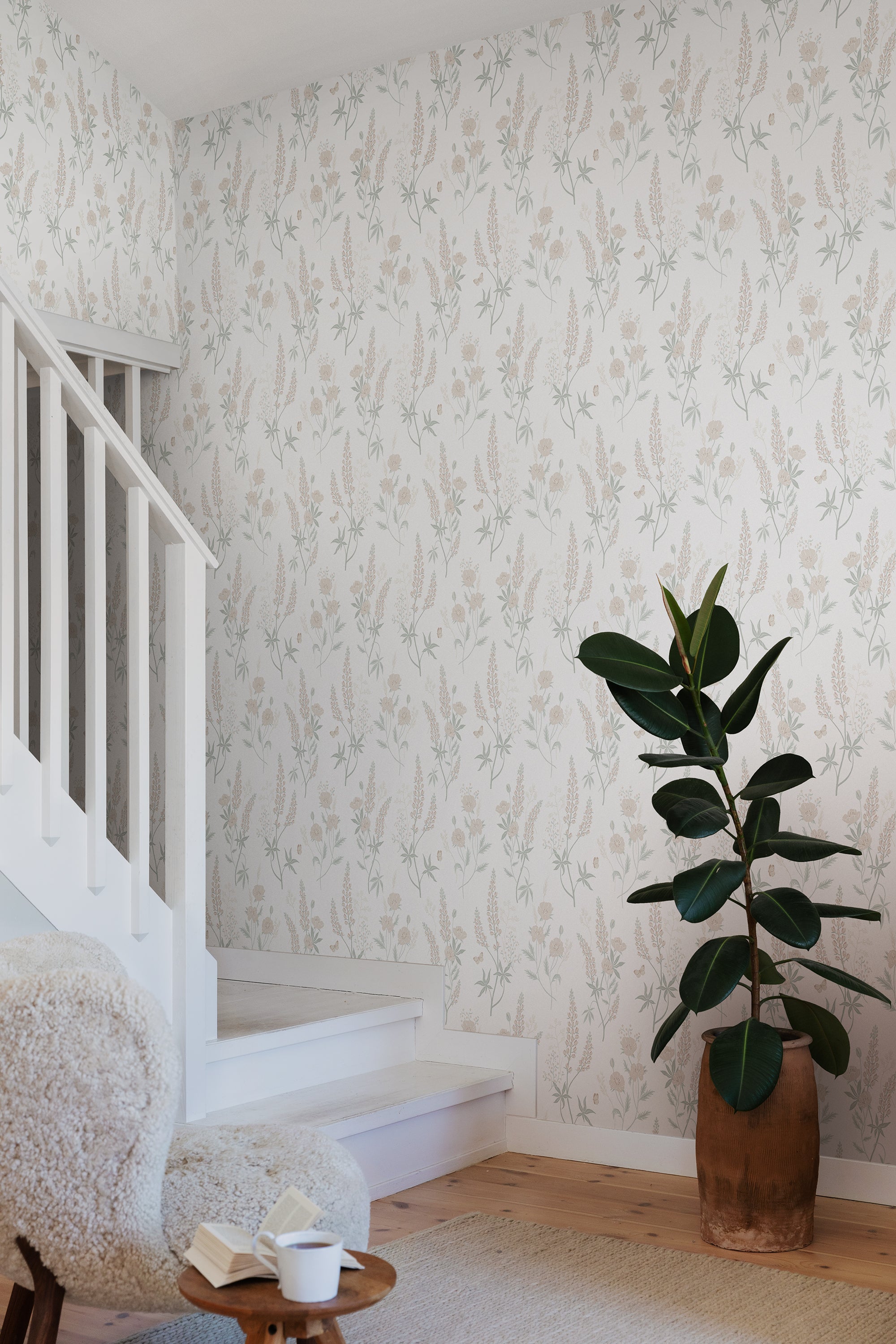 Emma wallpaper by Sandberg in soft beige with lupins and poppies in a stairwell with sheepskin chair and rubber plant
