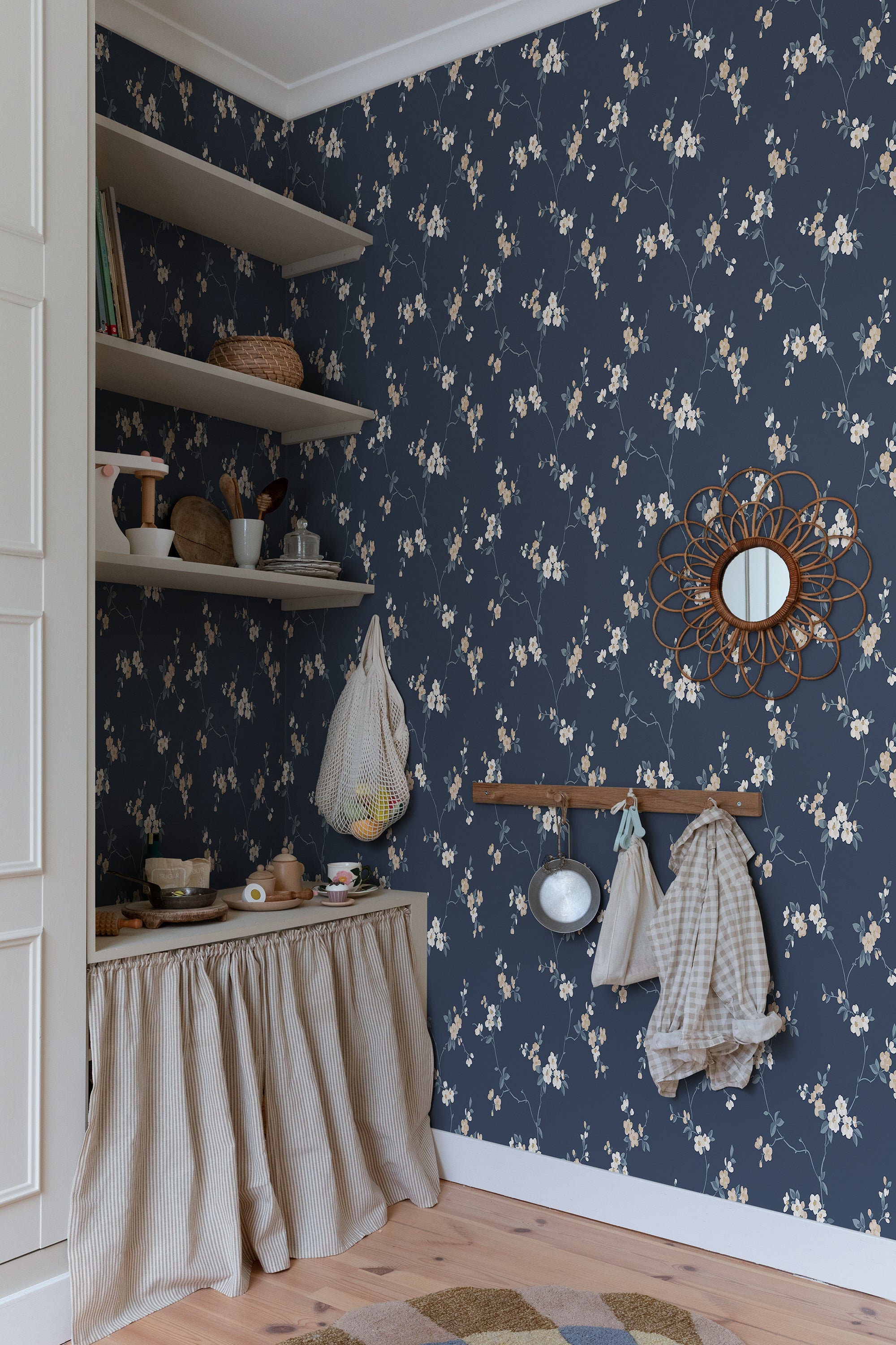 Navy Engla blossom wallpaper by Sandberg in a pantry corner with open shelves and a rattan mirror