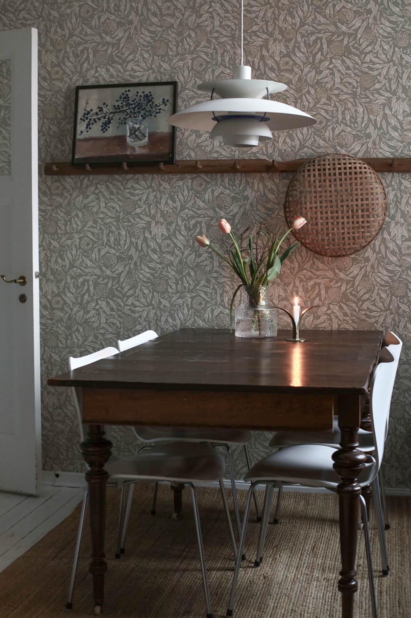 Olof wallpaper by Sandberg in greige in a dining room with a dark timber table, tulips and a Danish pendant light