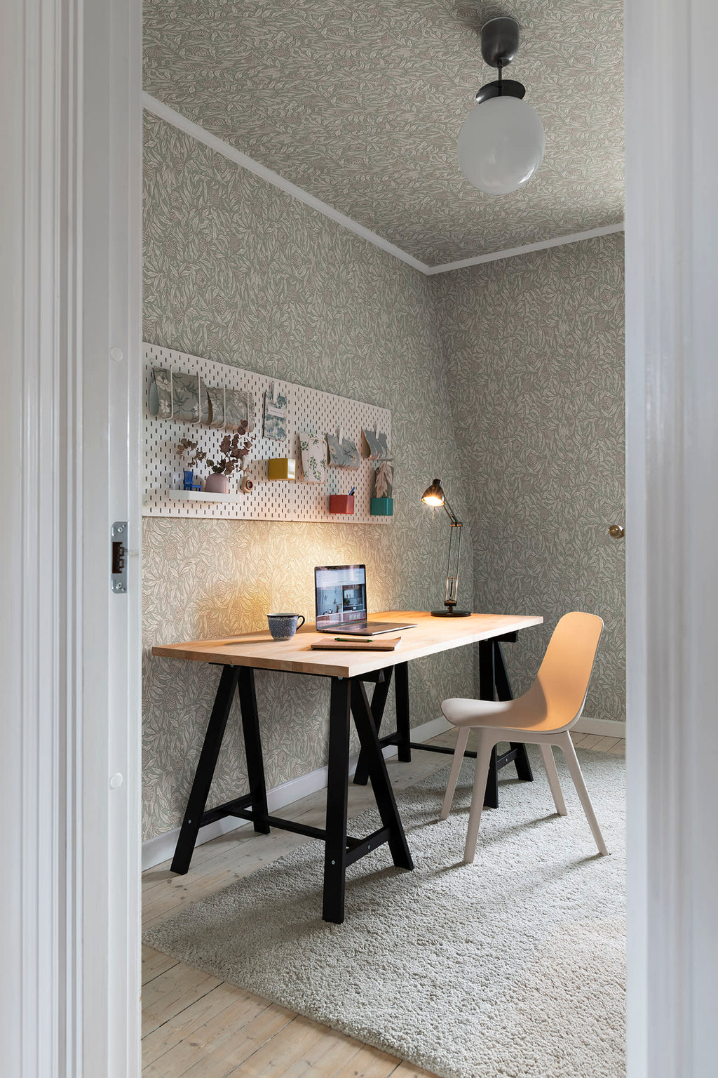 Olof wallpaper by Sandberg in muted green styled in a home office with a trestle desk, laptop and pale chair