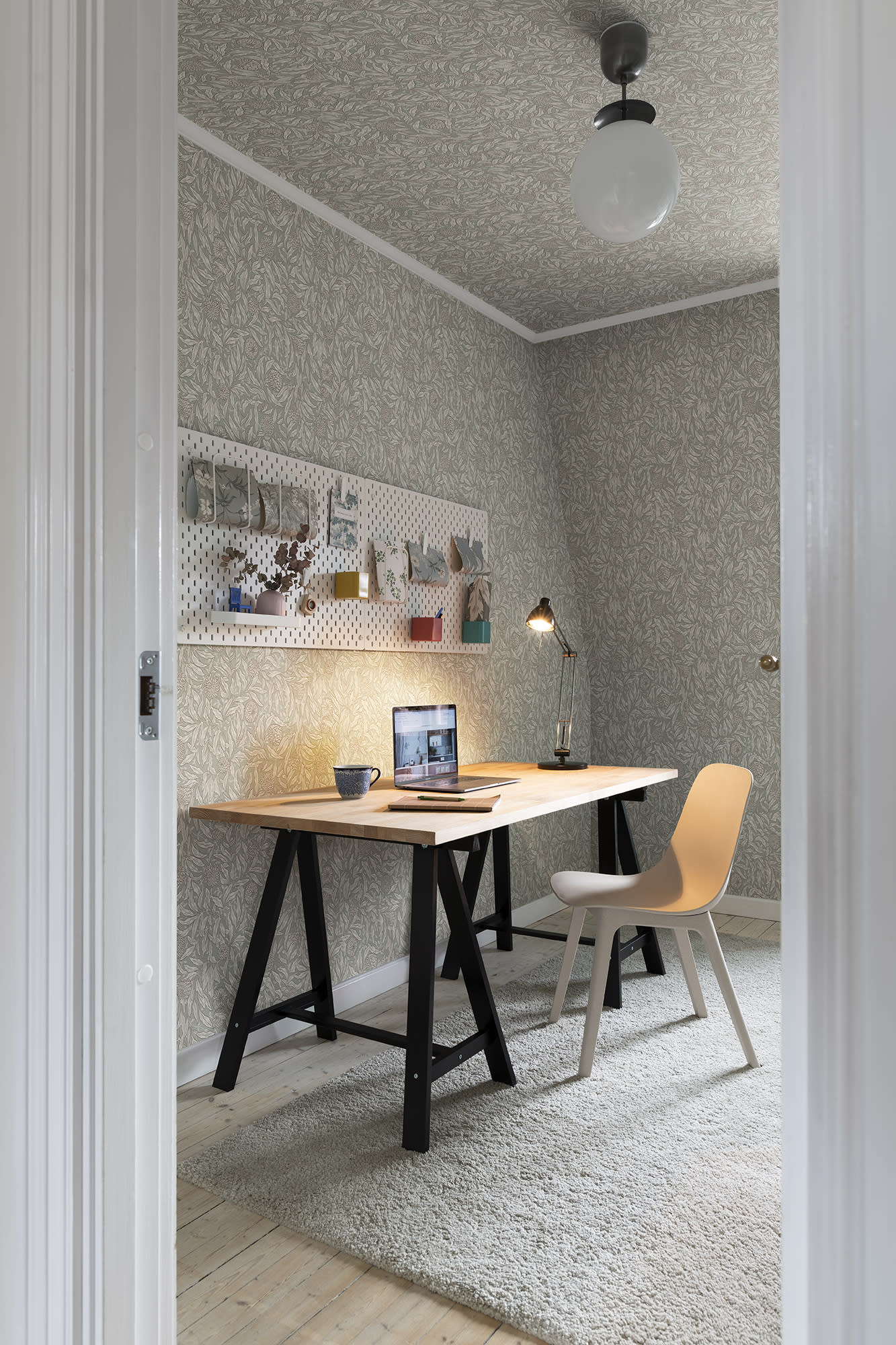 Olof wallpaper by Sandberg in muted green styled in a home office with a trestle desk, laptop and pale chair