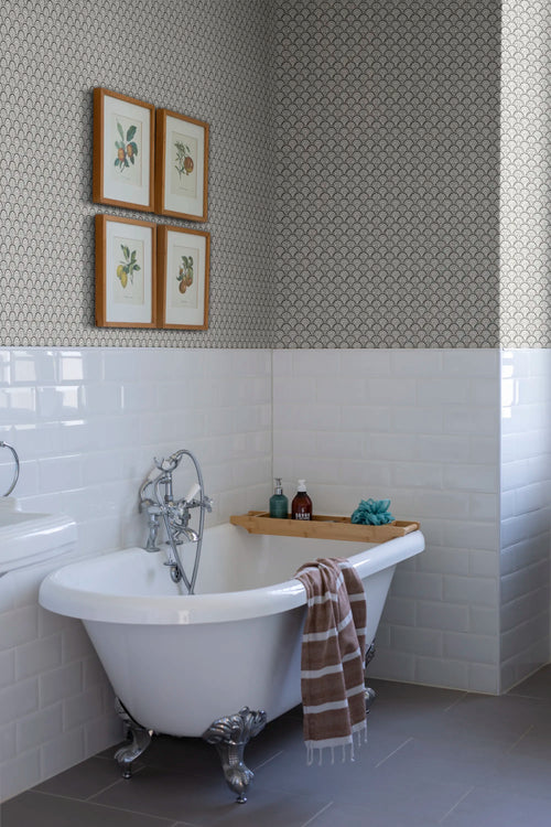 Beata wallpaper by Sandberg in a bathroom corner, charcoal fan-scallop pattern over metro tiles beside a clawfoot tub and framed fruit prints