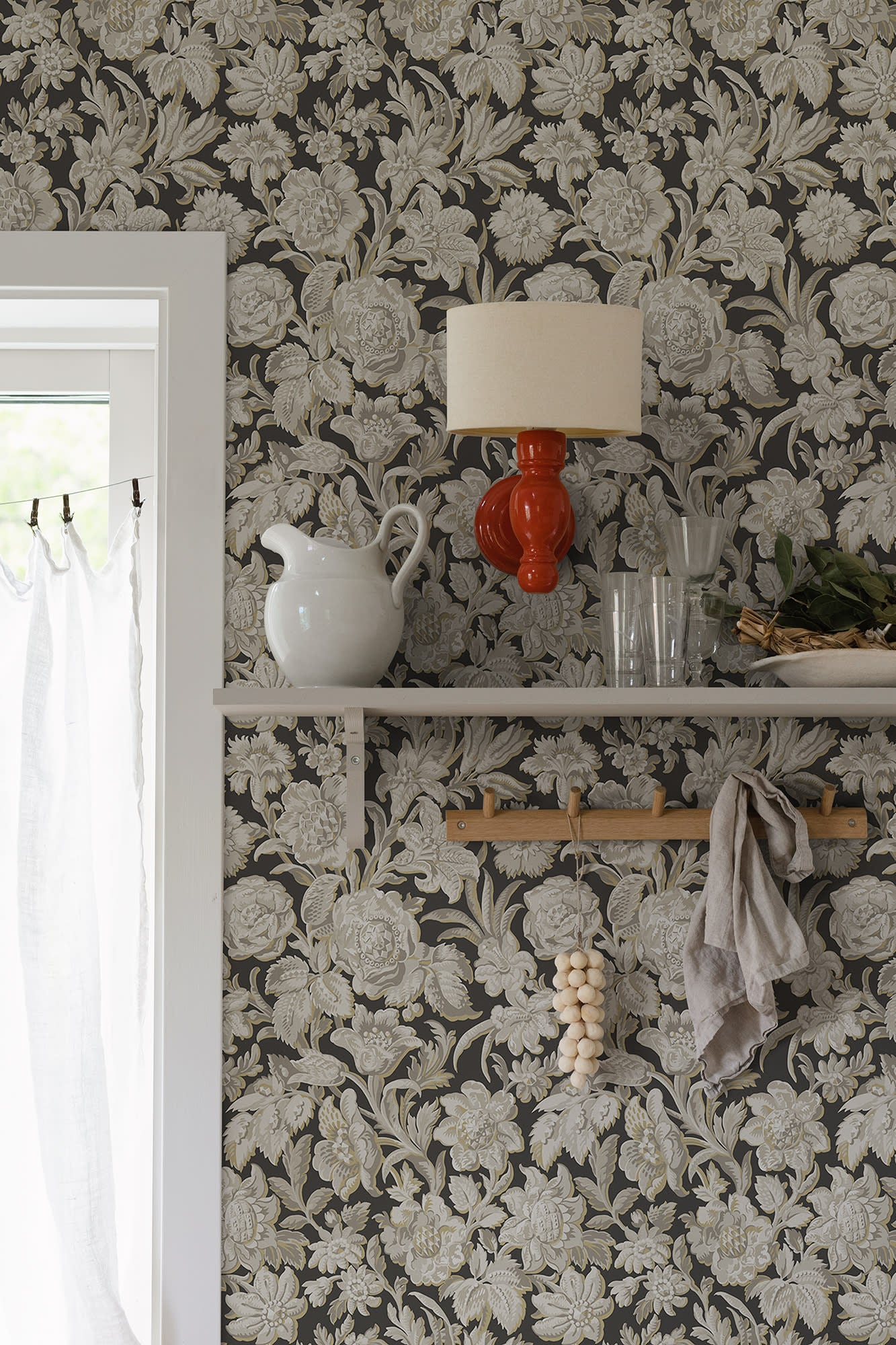 Valentin wallpaper by Sandberg in charcoal styled behind a shelf with a red lamp and white pitcher