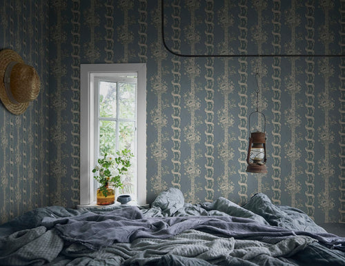 Alexandra wallpaper by Sandberg in dusty blue styled in a bedroom with rumpled linen, a window and hanging lantern