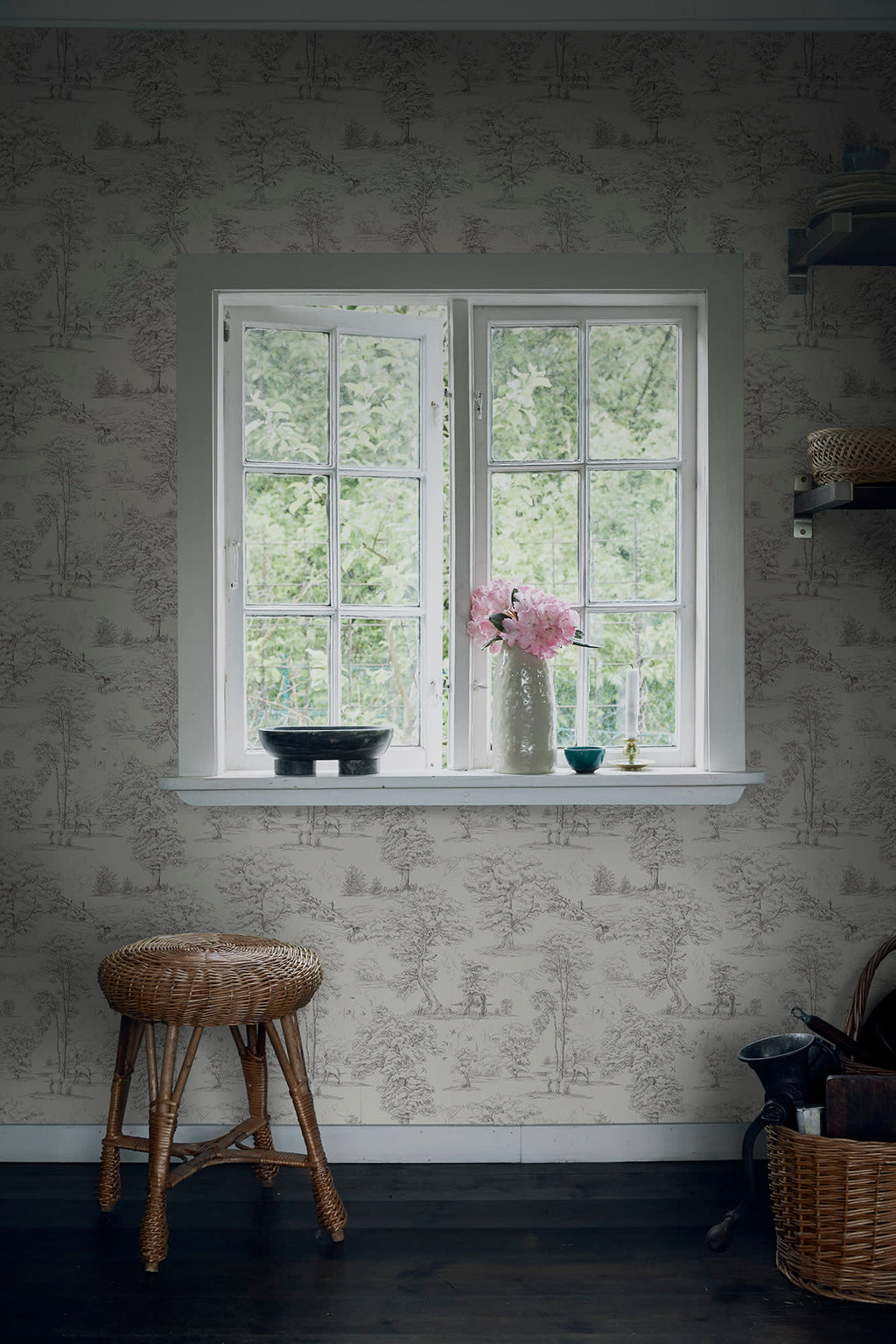 Grey Montfort toile wallpaper by Sandberg around a cottage window with peonies and a rattan stool