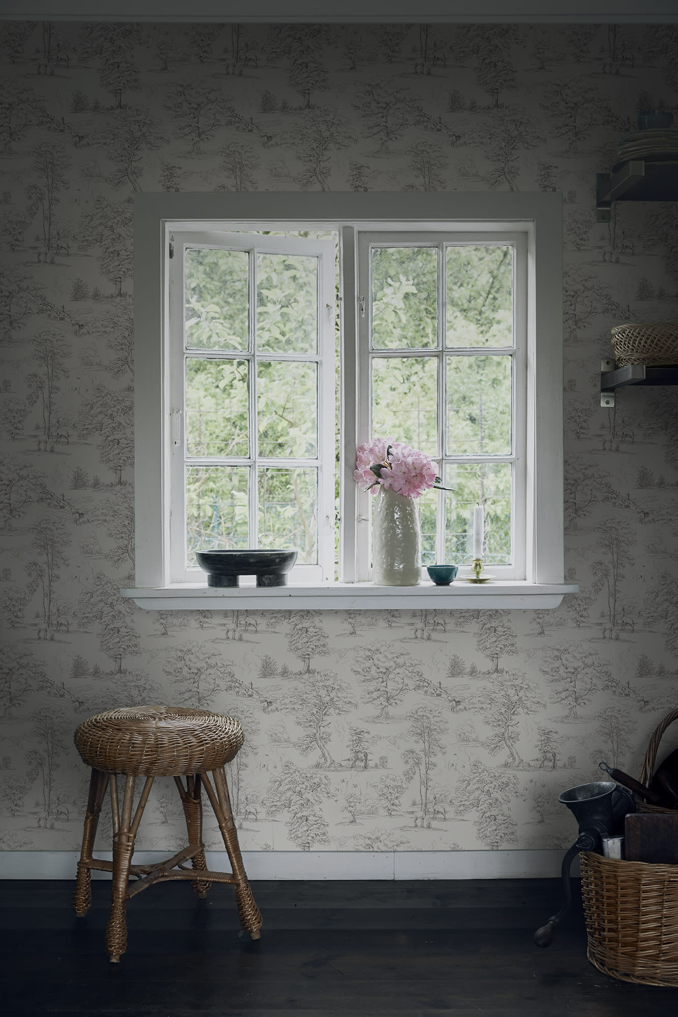 Grey Montfort toile wallpaper by Sandberg around a cottage window with peonies and a rattan stool