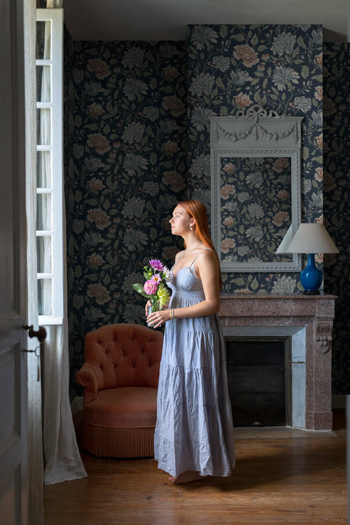 Annabelle wallpaper by Sandberg in navy floral in an elegant room, close view of fireplace, mirror and blush armchair