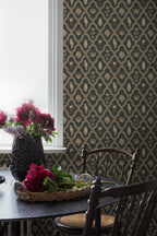 Turtledove Barn wallpaper by Sandberg in charcoal and gold styled in a dining room with a window, dark chair and pink peonies