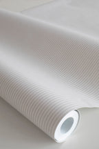 Rand Stripe wallpaper by Sandberg in greige, close-up of a wallpaper roll showing a fine ticking pinstripe
