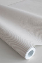 Rand Stripe wallpaper by Sandberg in soft sand, close-up of a wallpaper roll showing a fine ticking pinstripe