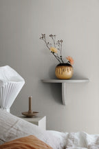 Rand Stripe wallpaper by Sandberg in soft sand, styled above a bed beside a white wall shelf with drip-glazed vase