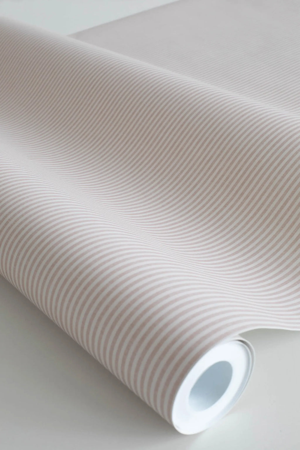 Rand Stripe wallpaper by Sandberg in warm taupe, close-up of a wallpaper roll showing a fine ticking pinstripe