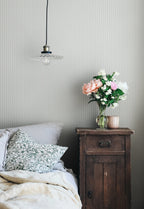 Rand Stripe wallpaper by Sandberg in soft sage-grey, styled in a bedroom with glass pendant, antique nightstand and flowers