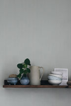 Rand Stripe wallpaper by Sandberg in soft sage-grey, styled above a timber shelf with jug, plant and ceramic bowls