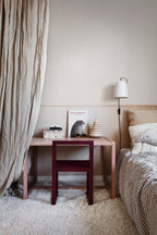 Ruta wallpaper by Sandberg in beige check in a child bedroom with a pink desk, burgundy chair and wall light