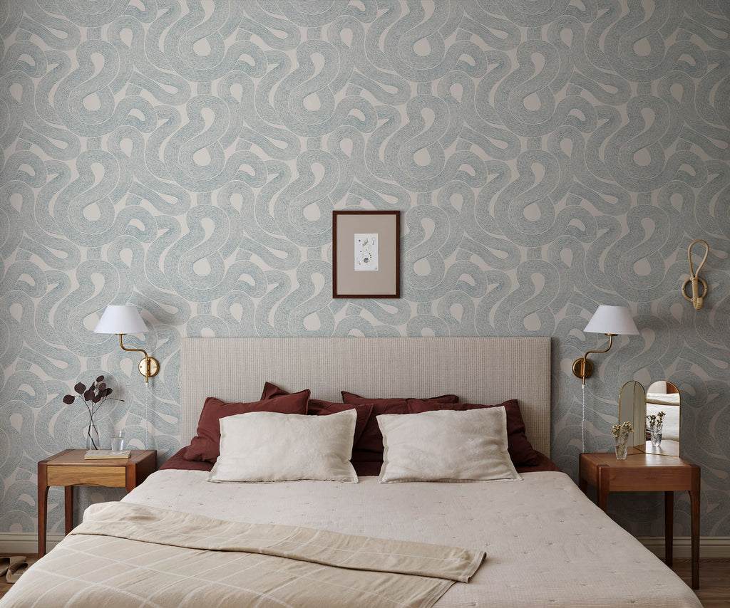 Zen wallpaper by Sandberg in blue looping print behind a bed with red and ivory linens and wall sconces