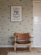 Gillis blue star mural by Sandberg behind a tan leather chair and framed vintage poster.