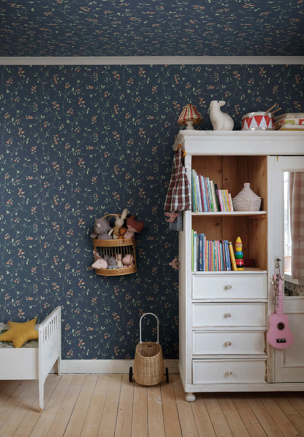 Sanna Sweet Pea wallpaper by Sandberg in navy blue coral sweet pea print in a childrens room with a white toy cabinet