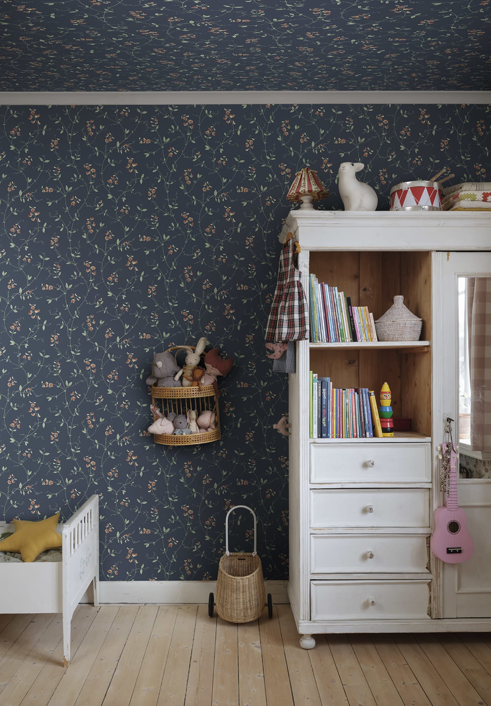 Sanna Sweet Pea wallpaper by Sandberg in navy blue coral sweet pea print in a childrens room with a white toy cabinet