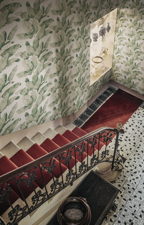 Tom Palms wallpaper by Sandberg in green banana leaves on a stairwell wall above a red-carpeted staircase
