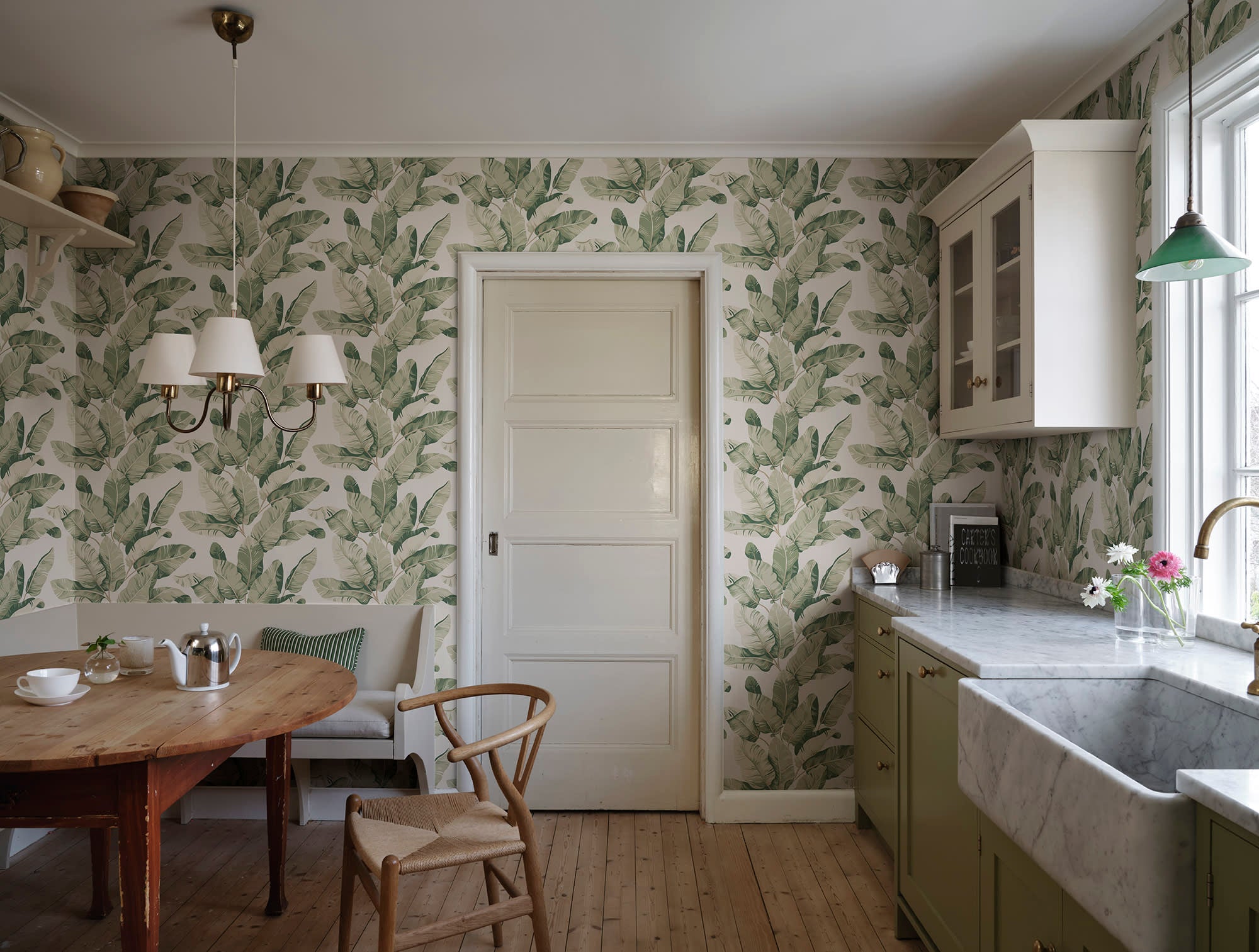 Tom Palms wallpaper by Sandberg in sage-green banana leaves styled in a kitchen dining nook