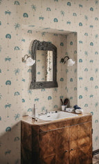 Milo Palms wallpaper by Sandberg in teal on cream, styled in a bathroom around a carved mirror and twin glass sconces