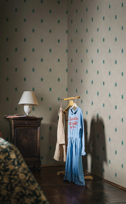 Audrey wallpaper by Sandberg in green wrapping a moody bedroom corner with a lamp and parquet floor