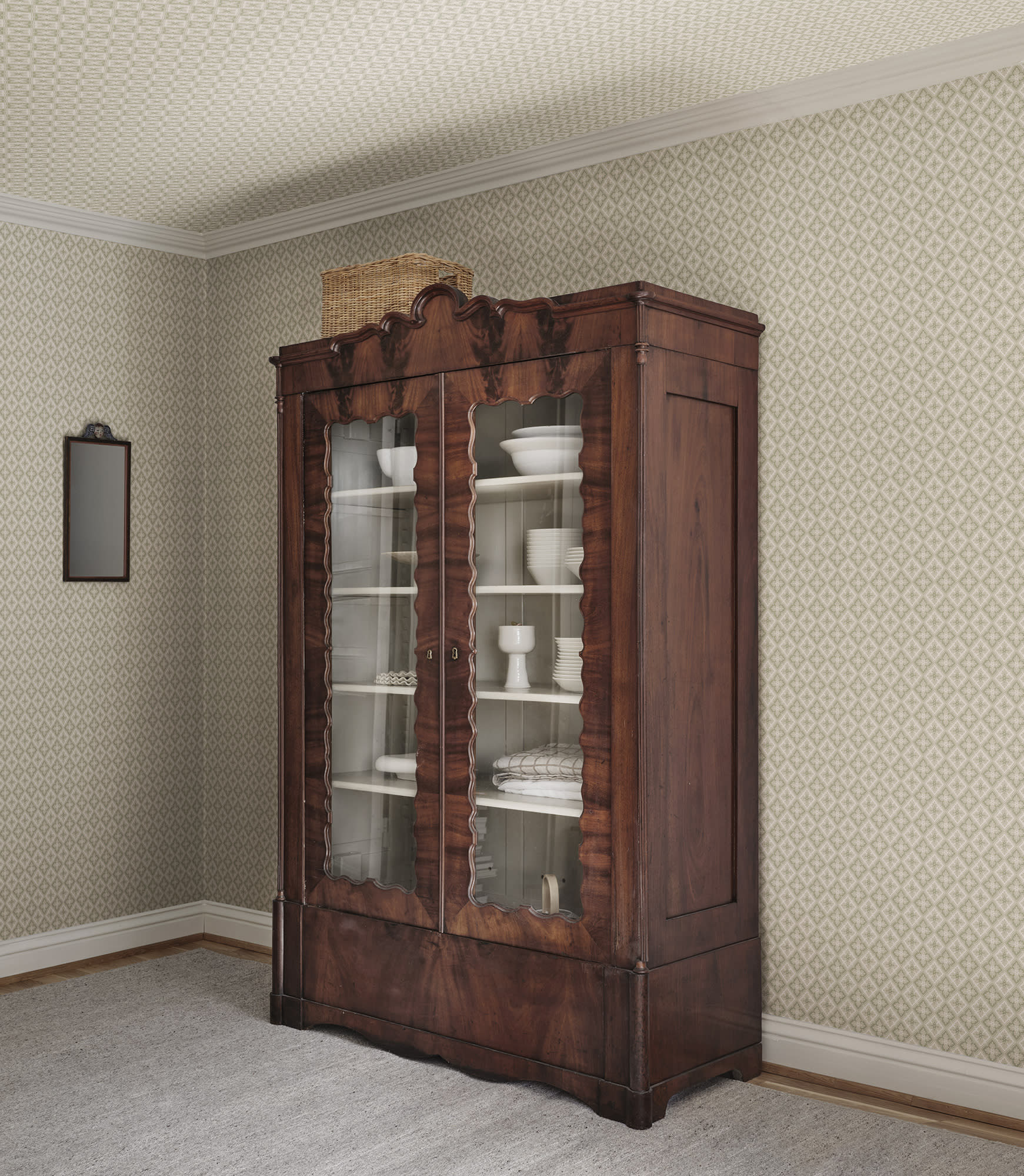 Edvin wallpaper by Sandberg in sage green in a dining room behind an antique mahogany china cabinet