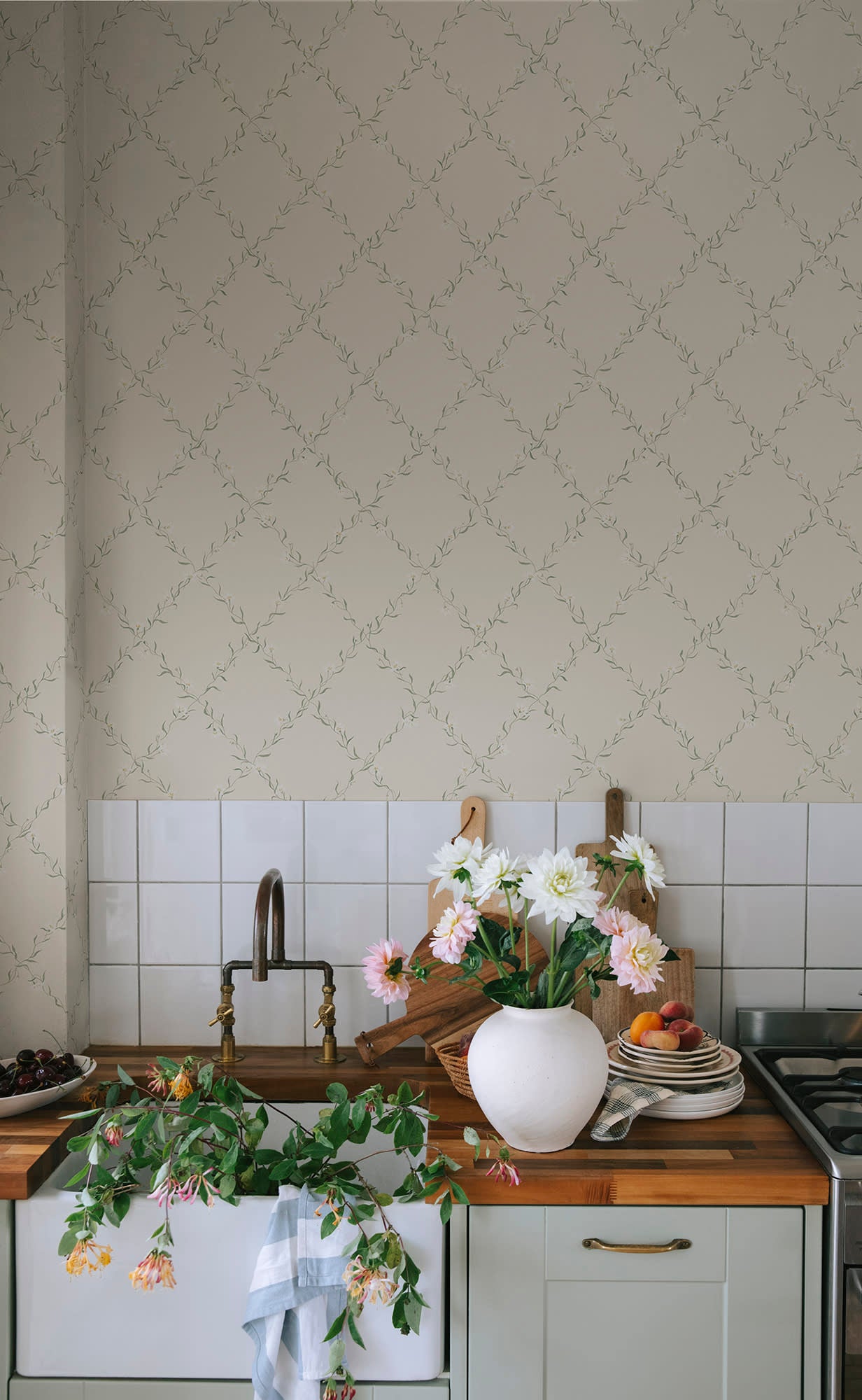 Ewa wallpaper by Sandberg in soft greige with a floral trellis vine above a tiled kitchen sink and dahlias
