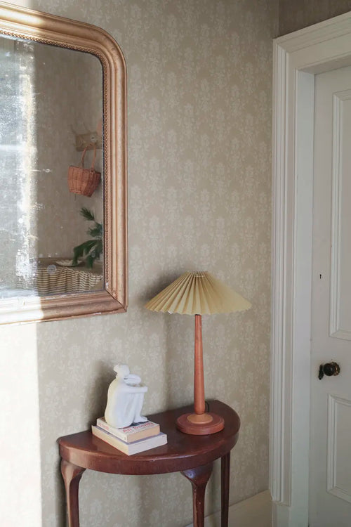 Alva wallpaper by Sandberg in beige styled in a hallway with a gilt mirror and pleated lamp