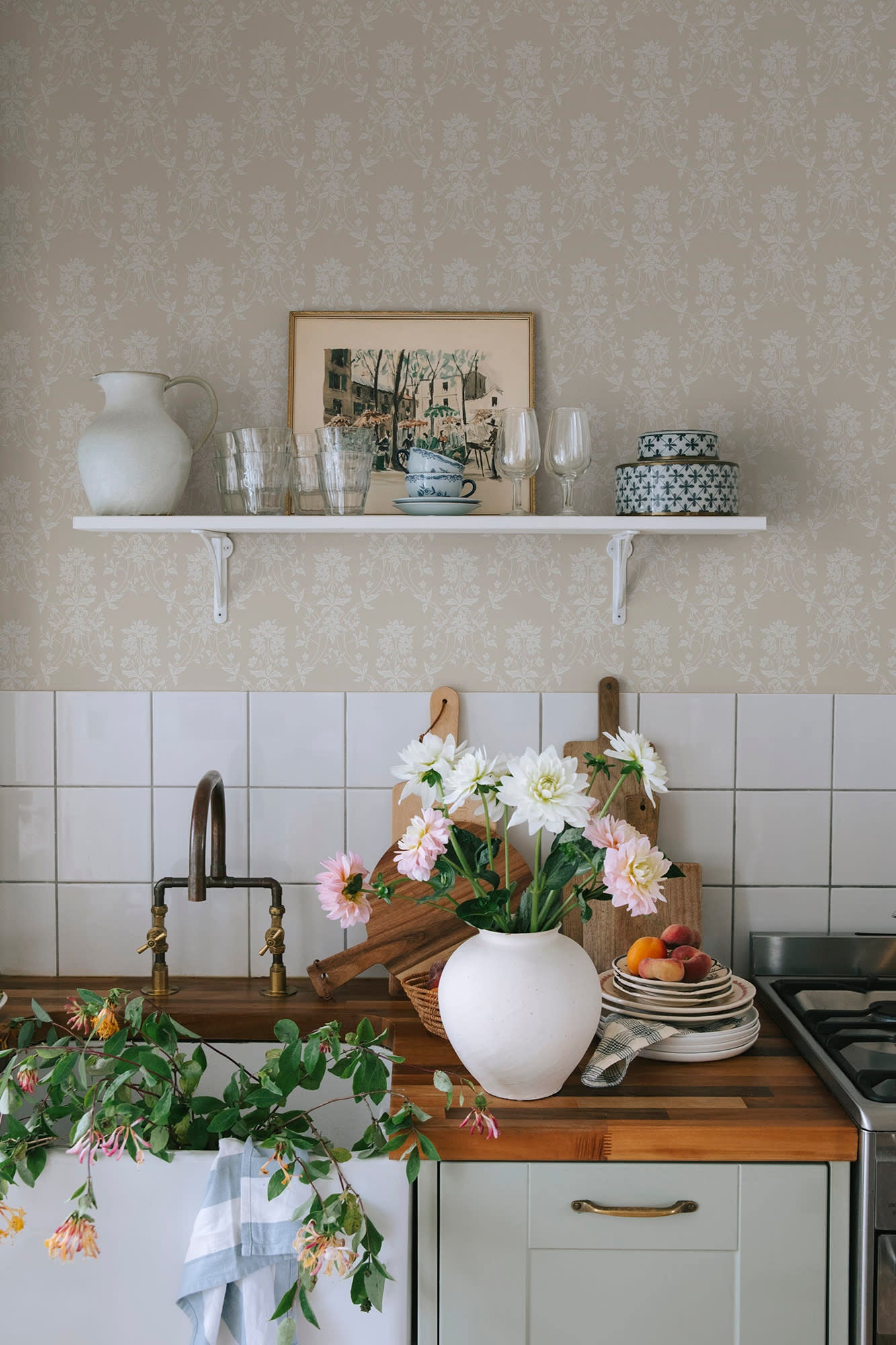 Alva wallpaper by Sandberg in beige in a kitchen above a shelf with dahlias and white tile splashback