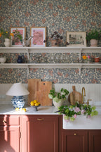 Emrik wallpaper by Sandberg in blue and terracotta above open kitchen shelves with rust cabinets and a butler sink