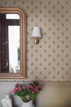 Siv wallpaper by Sandberg in burgundy, close-up beside a gilt mirror and brass wall sconce