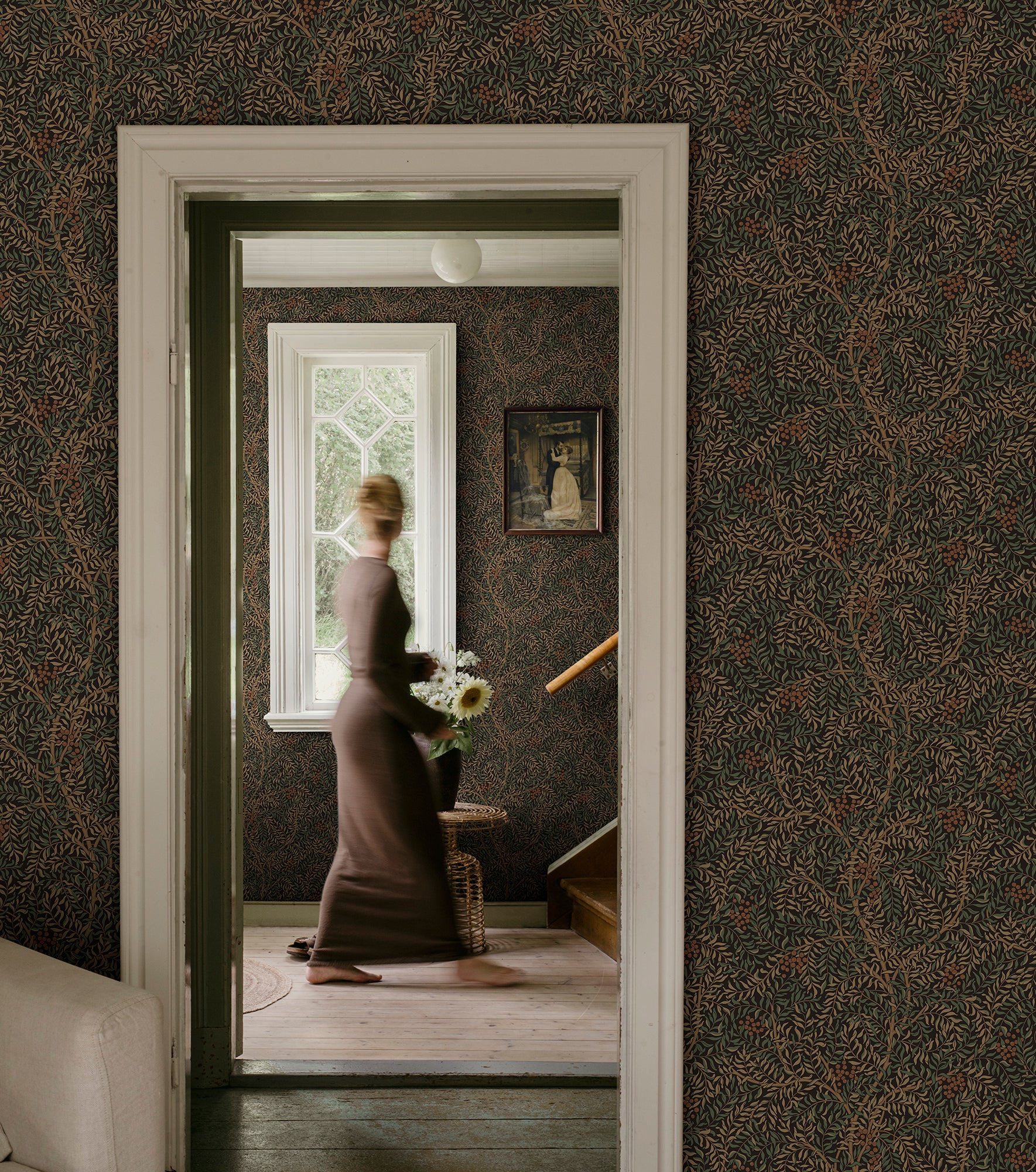 Simon wallpaper by Sandberg in dark green in a hallway framing a woman in a doorway by a window