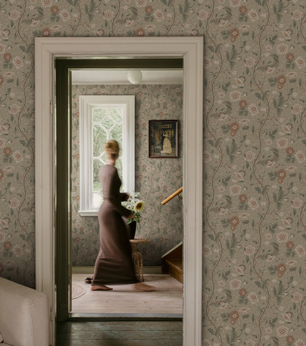 Ulla wallpaper by Sandberg in sage tones styled across a period hallway with a woman walking past a window