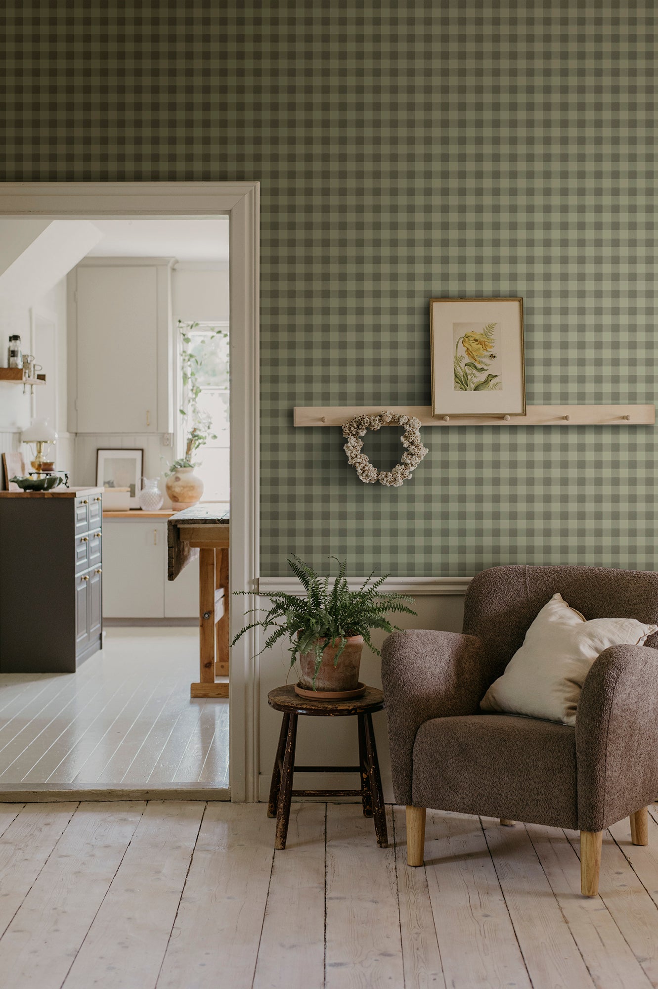Harry wallpaper by Sandberg in olive green in a living room with a boucle armchair, framed print and wreath