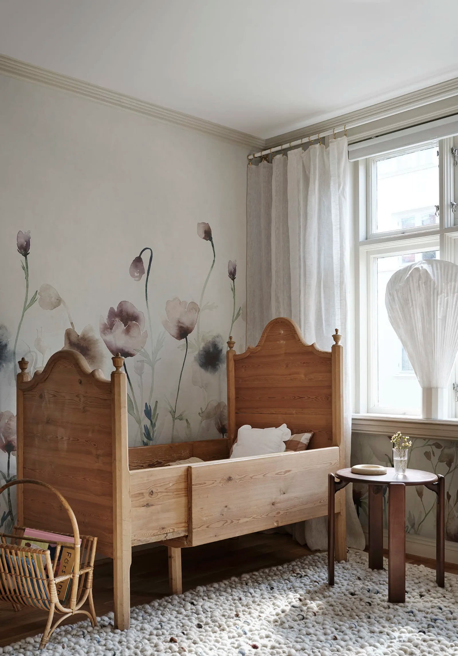 Morängen Floral wall mural by Sandberg in soft pink styled in a nursery behind a wooden childrens bed