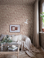 Tree of Life wallpaper by Sandberg in rust-red, styled in a cosy living room behind a grey sofa with framed art and throw