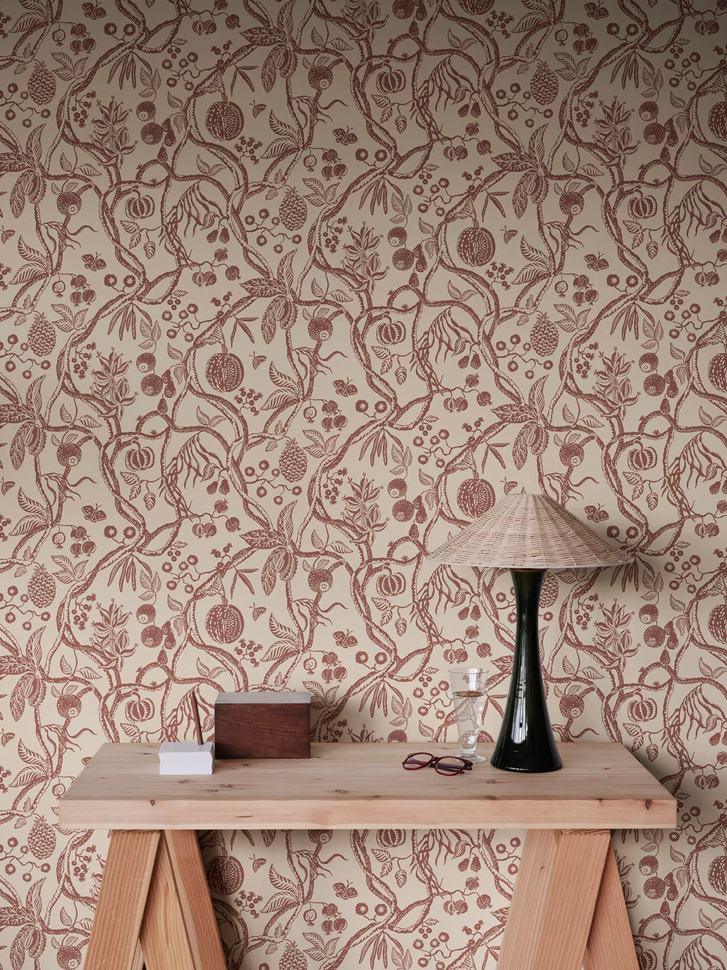 Tree of Life wallpaper by Sandberg in rust-red trailing fruit branches on cream, styled above a timber console with rattan lamp